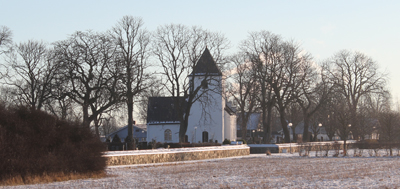 Bjuvs kyrka med härlig natur runtomkring. Nakna träd i bakgrunden och frost på gräset