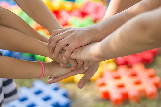 Barns händer förs sammanör att skapa en teamkänsla. Färgrik bakgrund