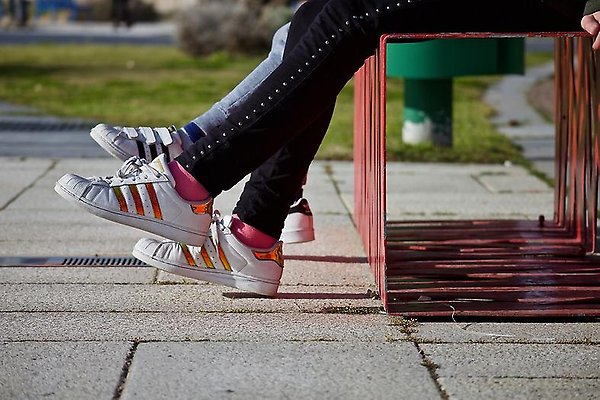Bild på ungdomars skor utomhus på en bänk